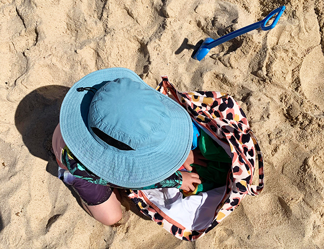 Boy looking in bag on beach