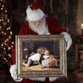 Santa peering down at a photo of two children in a frame