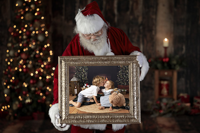Santa peering down at a photo of two children in a frame